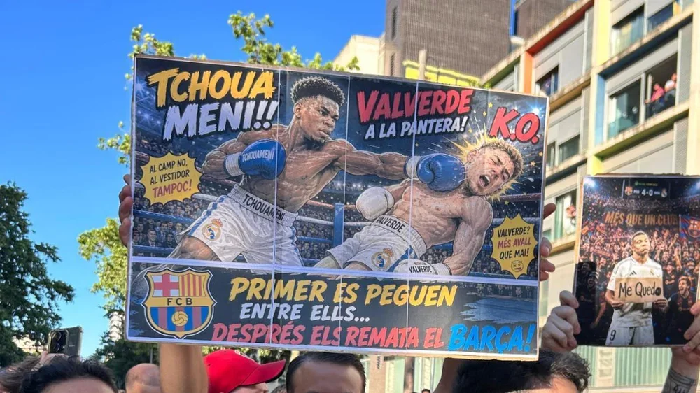 Un aficionado sostiene una pancarta de Valverde y Tchouaméni antes del clásico